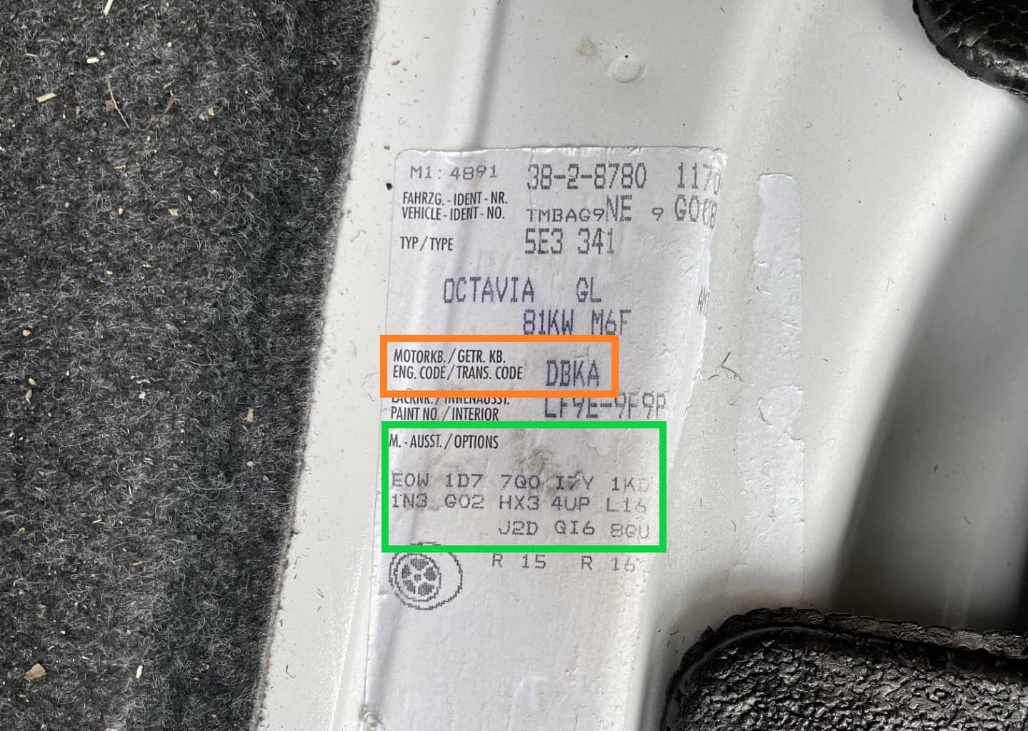 Motorkod och PR-nummer för en Skoda Octavia på en dekal under bagagerumsmattan.
